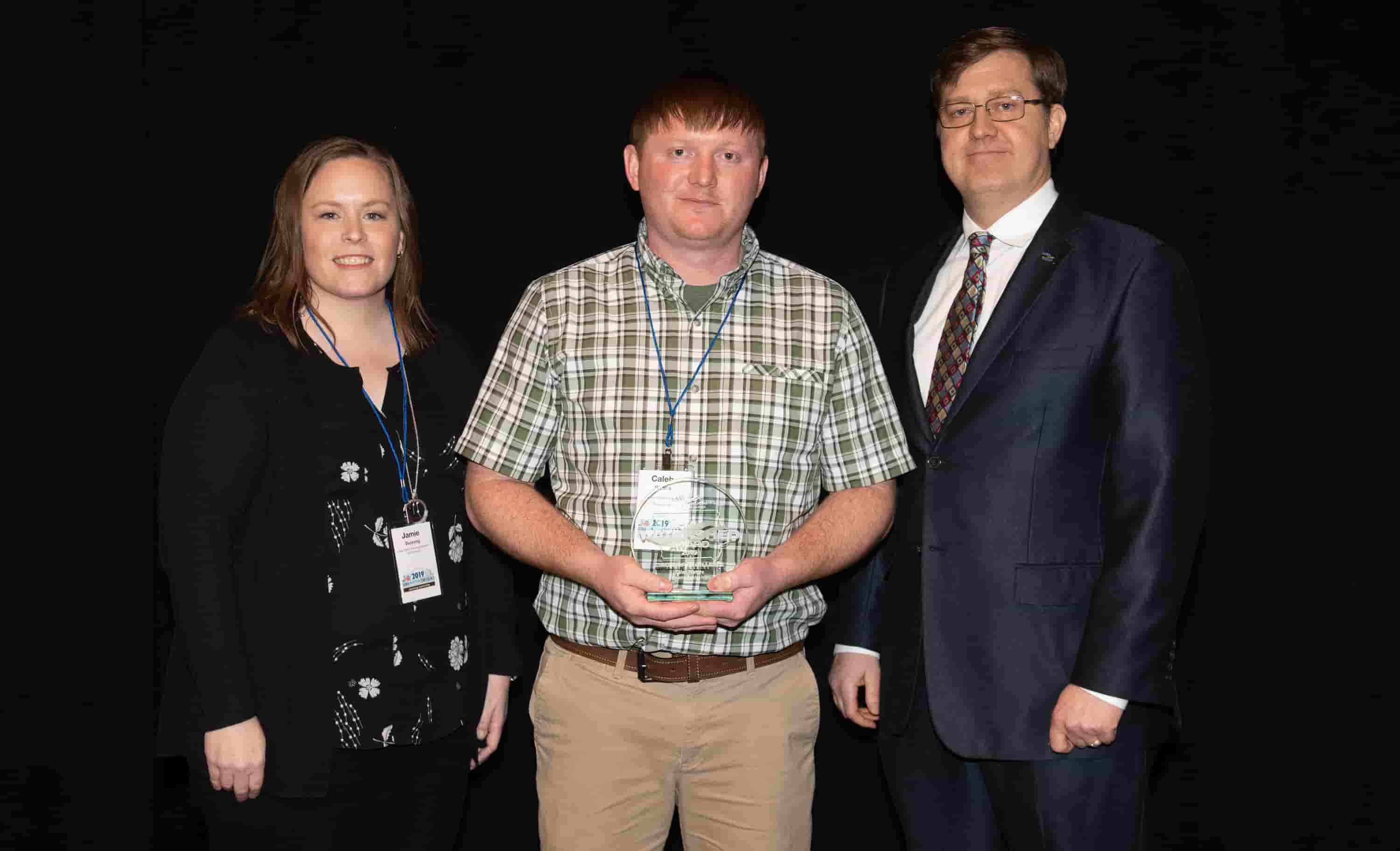 Jamie Benning with Iowa State University, Sean McMahon with Iowa Ag Water Alliance presenting Caleb Waters, watershed coordinator, with an IAWA Iowa Watershed Award