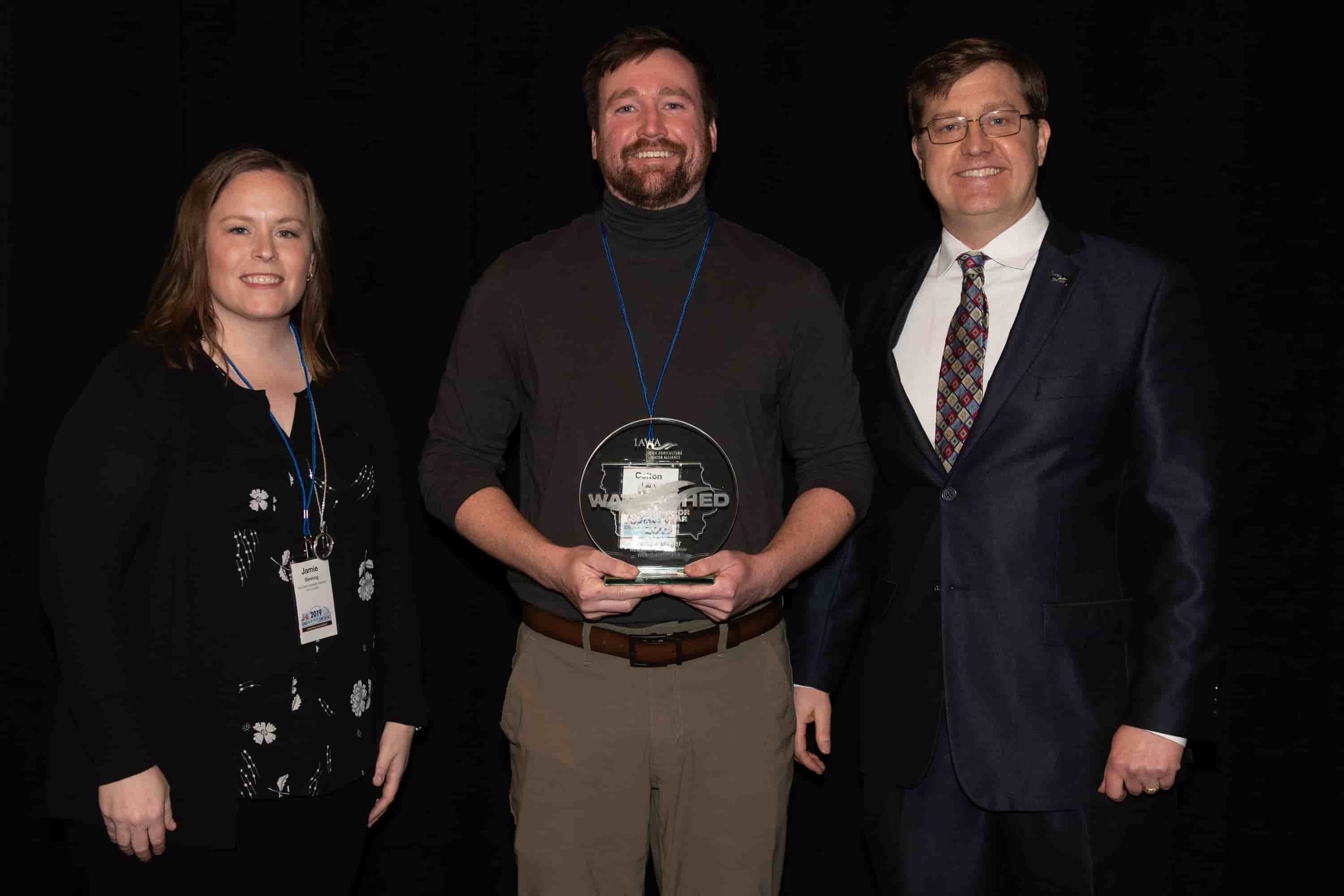 Jamie Benning with Iowa State University, Sean McMahon with Iowa Ag Water Alliance presenting Colton Meyer, watershed coordinator, with an IAWA Iowa Watershed Award