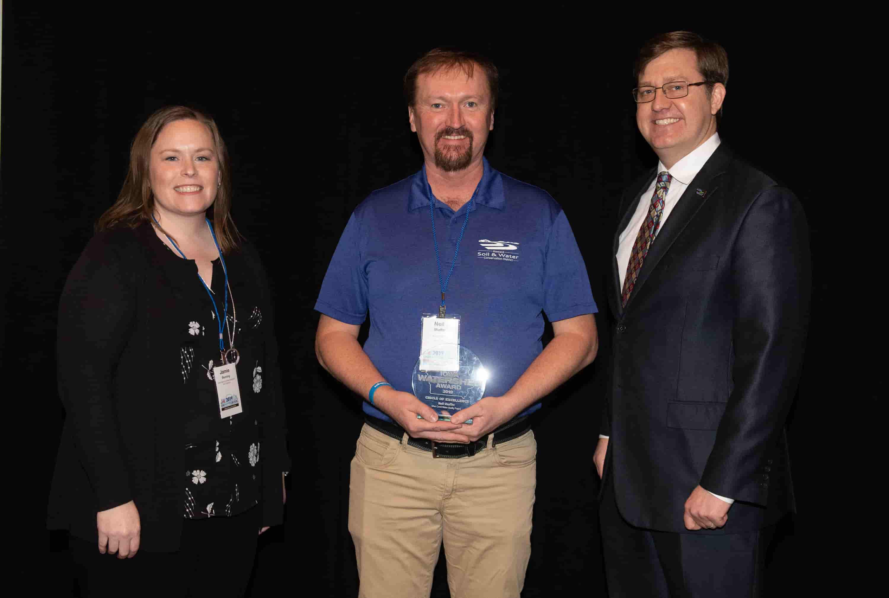 Jamie Benning with Iowa State University, Sean McMahon with Iowa Ag Water Alliance presenting Neil Shaffer watershed coordinator, with an IAWA Iowa Watershed Award