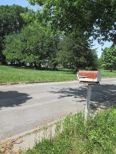 A rusty mailbox remains on a house lot on a nearly abandoned street in Des Moines